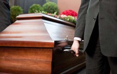 Religion, death and dolor - coffin bearer carrying casket at funeral to cemetery